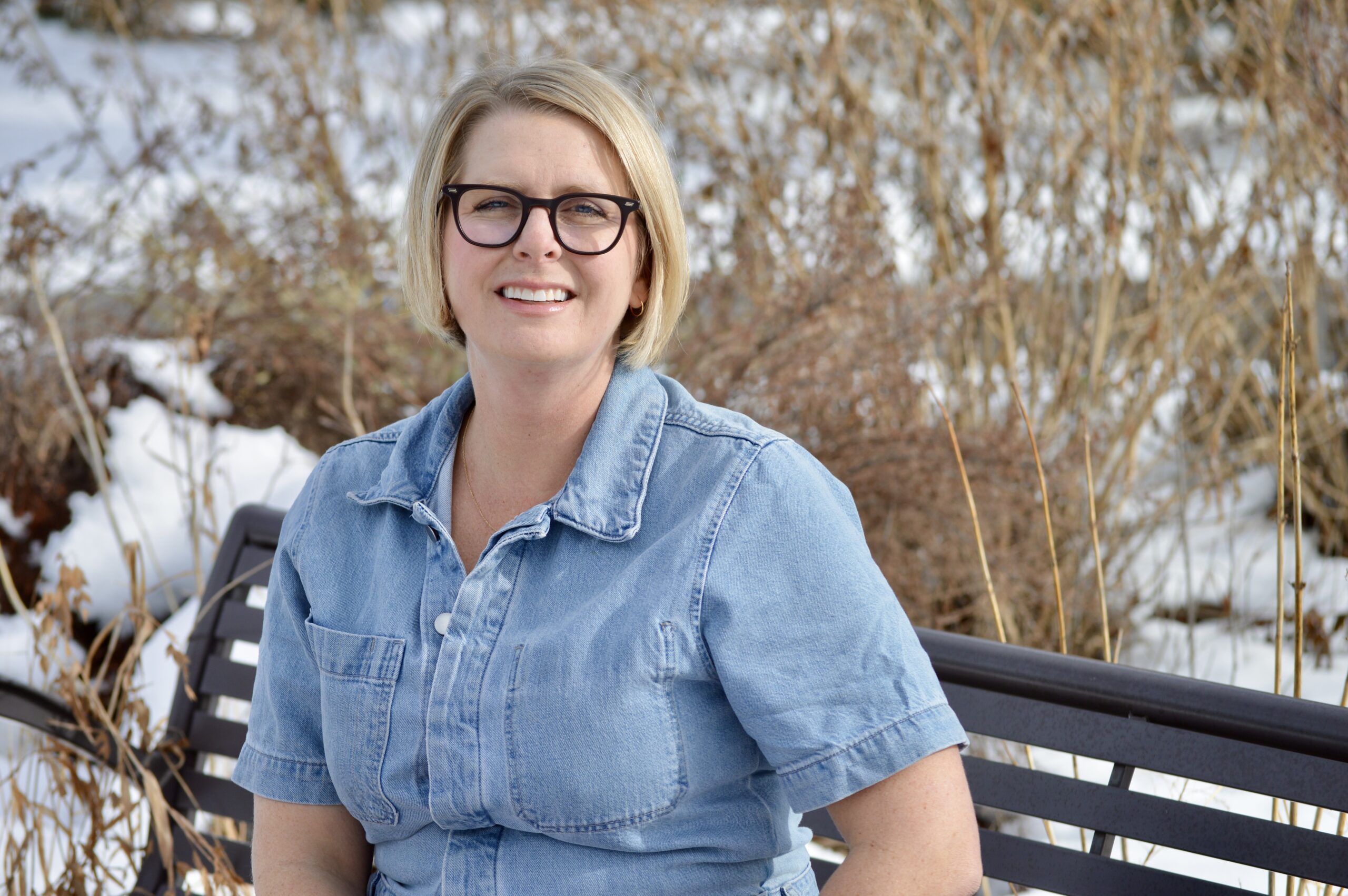 Woman sitting on bench in snowy park